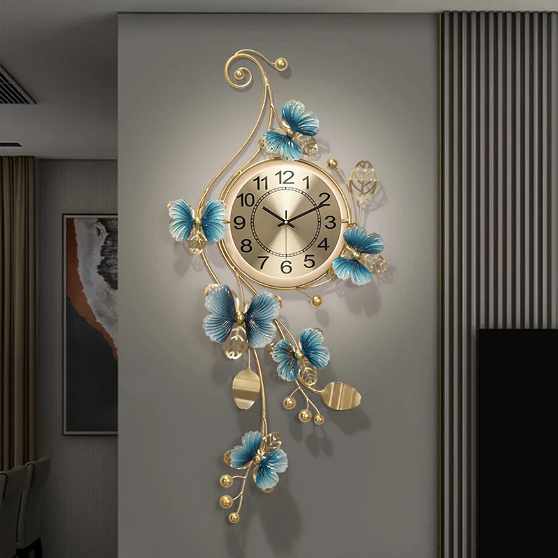 Hanging Wall Clock - Elmsford: A round, gold-toned clock with black numerals and ornate metal frame featuring scrolling stems and blue-and-gold flowers, perfect for adding a contemporary touch to any room.