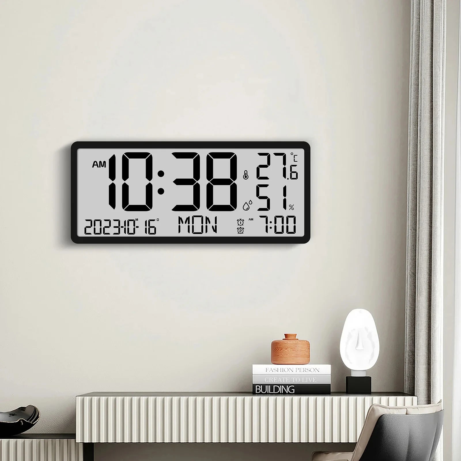 White Digital Clock - Carradon: A large wall-mounted digital clock displaying time, date, temperature, and humidity, positioned above a stylish console table with books, a lamp, and a decorative container.