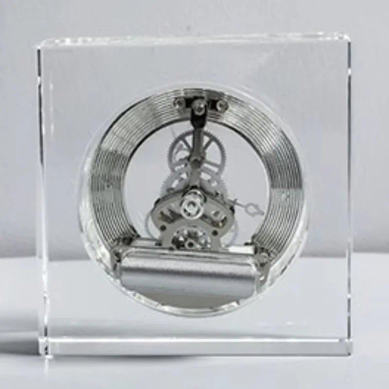 Crystal tabletop clock - Dunley: Showcasing a watch movement encased in clear acrylic, featuring a visible mainspring, gear train, and escapement, offering a sleek, modern touch to any desk or mantel.
