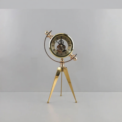 Vintage Table Clock - Gorven: A gold-coloured skeleton-style tabletop clock featuring visible internal gears, Roman numerals, and a tripod stand, adding vintage charm to any shelf or mantel.