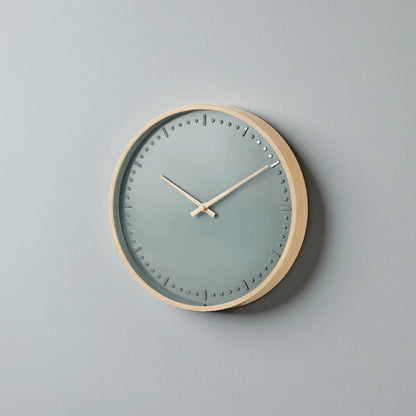 Small modern wall clock - Merrin: A minimalist wall clock with a light wood frame, muted gray-blue dial, and simple hour markers, blending Nordic design with silent German craftsmanship for a stylish, quiet focal point.