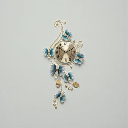 Hanging Wall Clock - Elmsford features a gold-faced dial with black numerals, encased in ornate metalwork with golden vines and blue floral accents, creating a sculptural, contemporary statement piece.