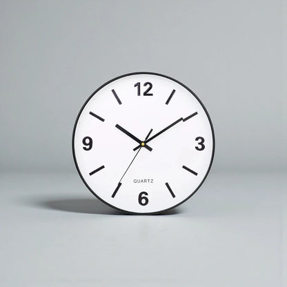 Modern Silent Wall Clock - Densford against a gray backdrop, showcasing its minimalist design with a white face, black hands, bold numerals at quarter hours, and silent quartz movement.