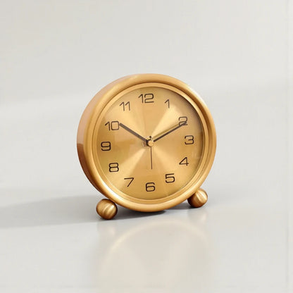 Brass Table Clock - Helric: A small, round analog clock with black numerals and three hands, featuring a polished and brushed brass finish, elegantly resting on two ball feet.