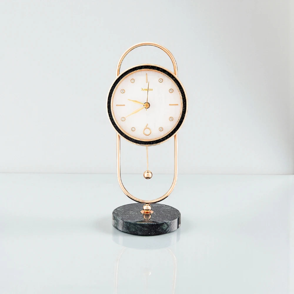 Pendulum Table Clock - Leiton: A decorative analog clock with a round white face, gold hands, and a pendulum, elegantly suspended in a gold frame with a dark marble base.