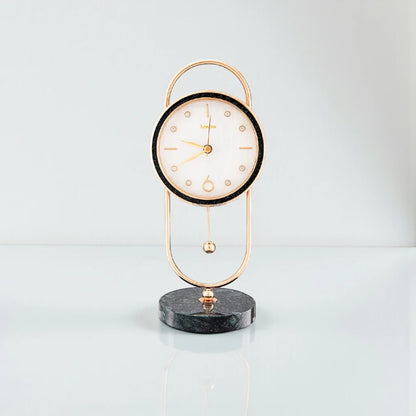 Pendulum Table Clock - Leiton: A decorative analog clock with a round white face, gold hands, and a pendulum, elegantly suspended in a gold frame with a dark marble base.
