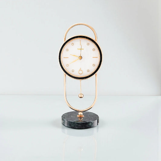 Pendulum Table Clock - Leiton: A decorative analog clock with a round white face, gold hands, and a pendulum, elegantly suspended in a gold frame with a dark marble base.