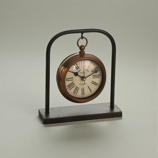 Retro Table Clock - Kelros: A charming, brass-colored desk clock styled like a pocket watch, featuring Roman numerals on its face, set on a sleek black metal arch.