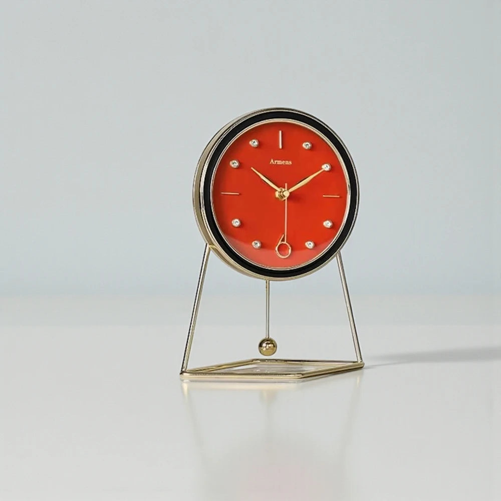 The Pendulum Table Clock - Dralen features a red dial, gold-tone hands, and a minimalist gold-metal stand with a swinging pendulum, blending classic and modern design elements.