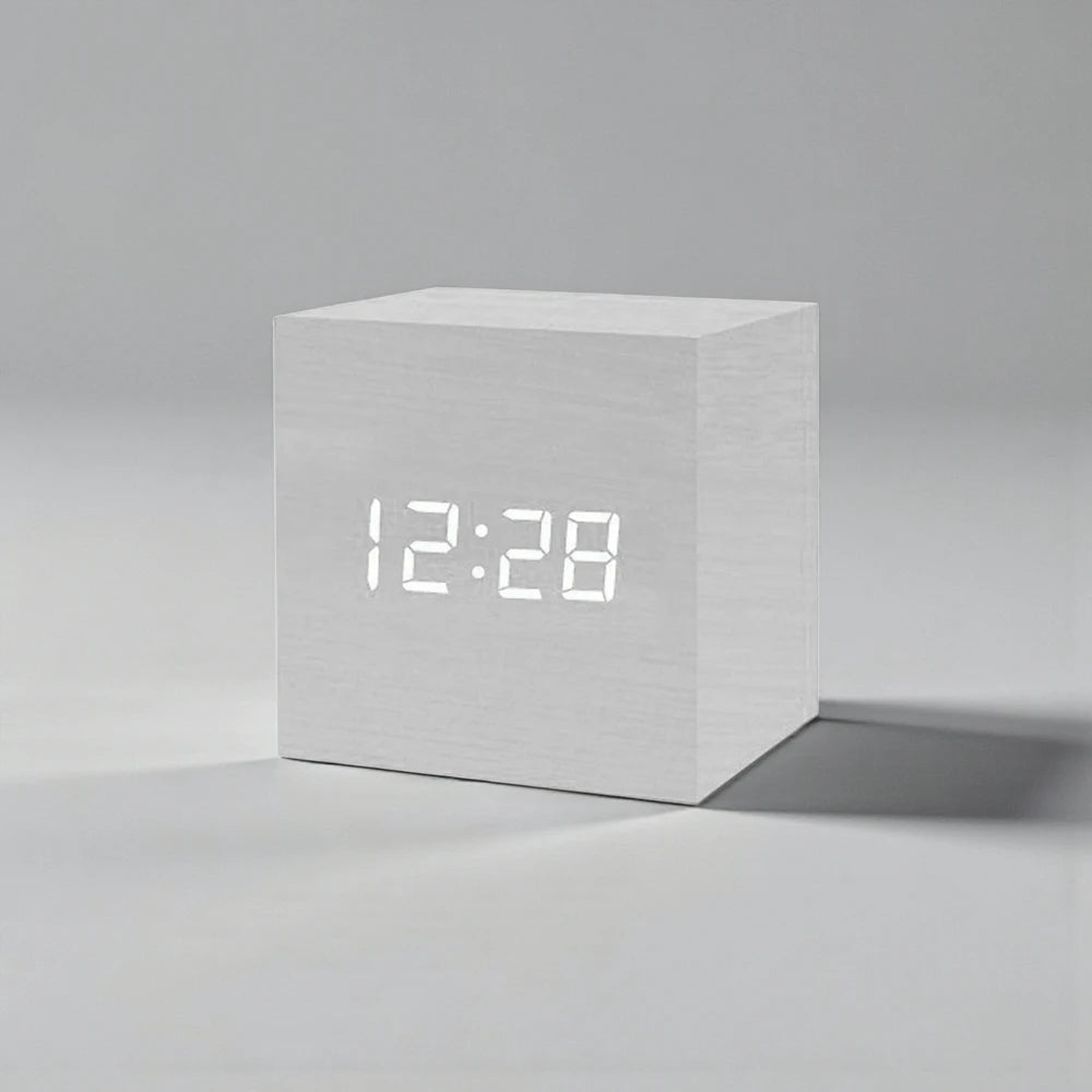 Cube Alarm Clock - Corven: A compact, cube-shaped digital clock with a light wood-grain finish and a clear white LED display showing “12:28,” ideal for enhancing your bedside table with modern elegance.