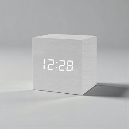 Cube Alarm Clock - Corven: A compact, cube-shaped digital clock with a light wood-grain finish and a clear white LED display showing “12:28,” ideal for enhancing your bedside table with modern elegance.