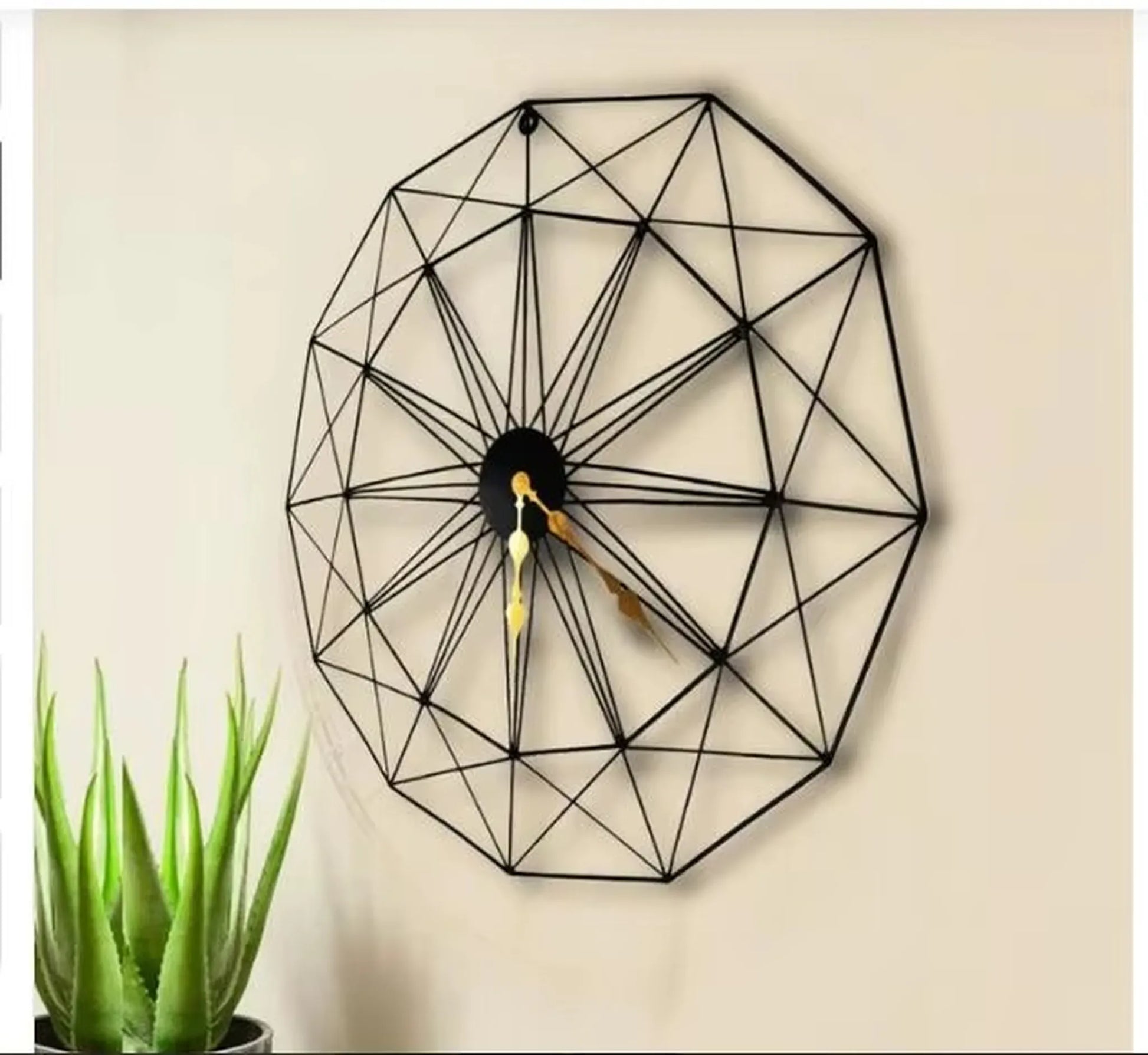 Modern Style Wall Clock - Blenford: A geometric black wireframe clock with gold hands, hanging on a beige wall. The design features interlocking triangles, complemented by a small potted succulent nearby.