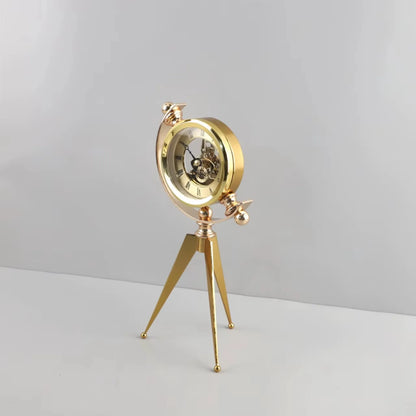 Vintage Table Clock - Gorven: A gold-tone mechanical skeleton clock with visible gears, mounted in a circular frame on a tripod stand, showcasing Roman numerals, perfect for adding vintage charm to any tabletop.