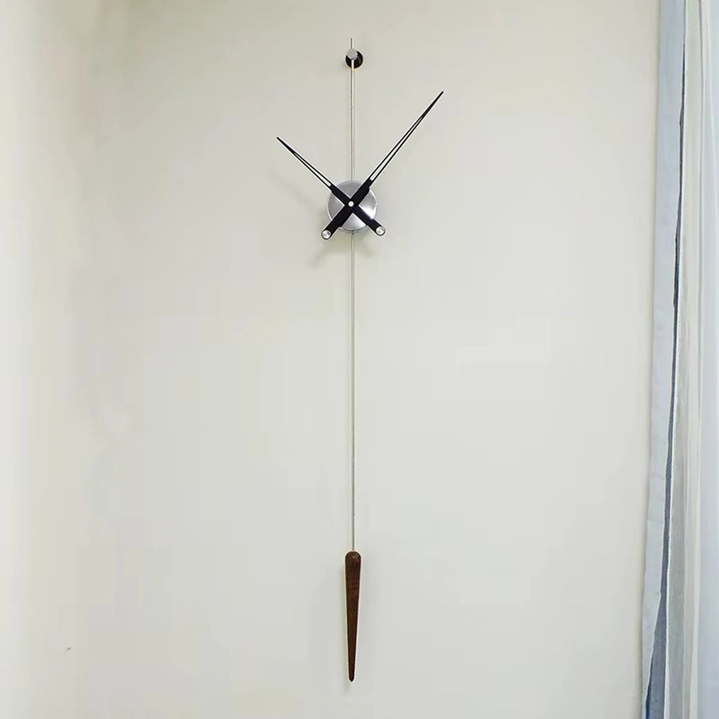 Mid century modern wall clock - Ellroy by The Horologista features slim black hands and a walnut pendulum, creating a minimalist, sculptural design with a 45-inch vertical baton on a plain wall.