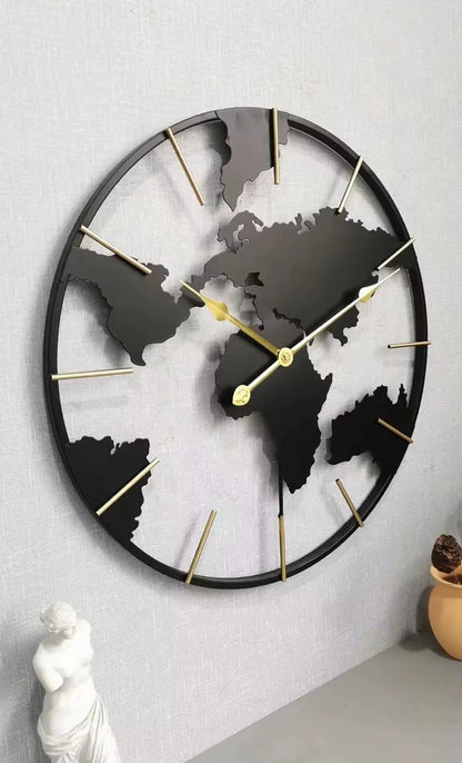 World Map Wall Clock - Claverton: A 23.6 black metal clock with continent silhouettes and gold-tone markers, elegantly mounted above a tabletop with a statuette, perfect for sophisticated living spaces.