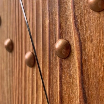 Wood Wall Clock - Stalford: Close-up of a wooden surface adorned with copper-colored studs and a diagonal stainless-steel wire, showcasing the craftsmanship of this statement clock from The Horologista.