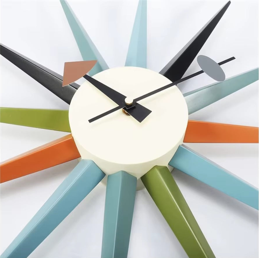 Rovell: A mid-century modern decorative clock with a round face and colorful radiating spokes featuring three distinct geometric hands.